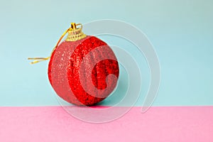 Red small round glass plastic xmas festive Christmas ball, Christmas toy plastered over sparkles on a pink purple blue background