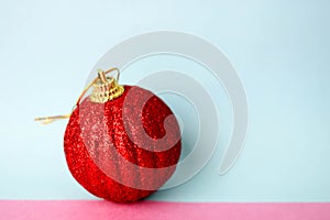 Red small round glass plastic xmas festive Christmas ball, Christmas toy plastered over sparkles on a pink purple blue background