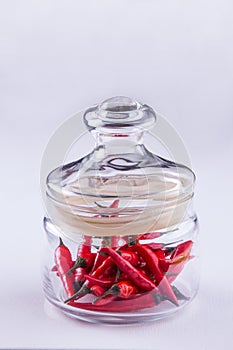 Red small spisy chili peppers in glass jar