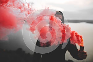 Red smoke bomb. Blurred image of ultras hooligan holding  smoke bomb in hand, standing on top of rock mountain with amazing view