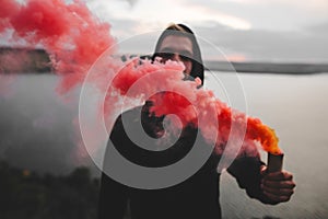 Red smoke bomb. Blurred image of ultras hooligan holding  smoke bomb in hand, standing on top of rock mountain with amazing view