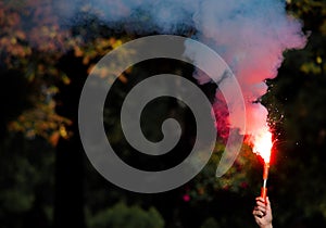 Red smoke bomb in a hand