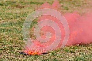 red smoke flare lying on a grassy field