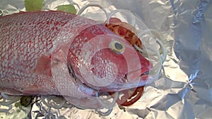 Red Snapper - Raw fish on tomatoes, olives and onions on tin foil