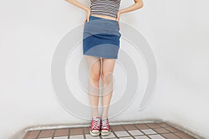 Red Sneakers of Free Space. Beautiful Slim Woman Legs with Red Shoes and Jean Skirt on Floor Background