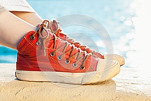 Red sneakers on girl and seascape as background