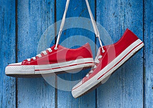 Red sneakers hanging on a wooden blue background