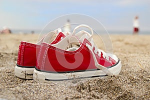 Red sneakers on sandy beach