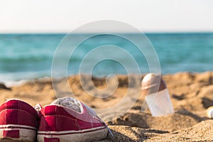 Red sneakers shoes and shaker left on the beach so people can go swimming. cant wait. relaxation. fun. carefree