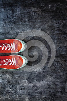 red sneakers with untied laces on a dark concrete background. Copy space. View from above