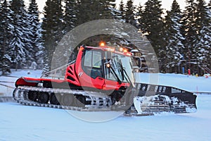 Red snow groomer in action, twilight after busy ski day