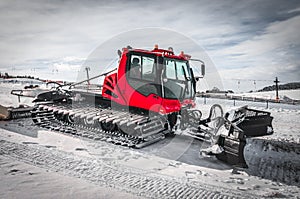 Red snow-grooming machine on snow