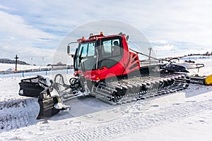 Red snow-grooming machine on snow