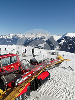 Red snowcat waits to groom the snow