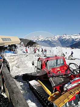 Red snowcat waits to groom the snow