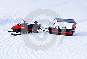 Red Snowmobile ski-doo with truck trailer. Skidoos parking in snow-white yard.