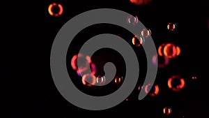 Red soap bubbles fly in the air. Slow motion. Black background