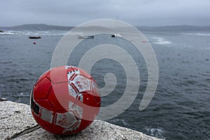 Red soccer ball on a scowling ocean