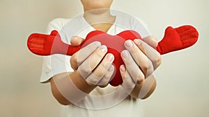 a red soft heart in the hands of a teenager on a light background. to give love