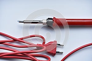 Red soldering iron on a white background. A tool for repairing electronics
