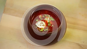 Red soup borsch with sourcream being prepaired and served at the restaurant kitchen