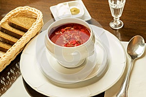 Red soup of vegetables borscht in the white bowl serving on the table of restaurant