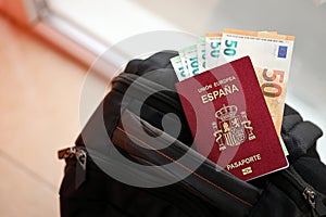 Red Spanish passport of European Union with money and airline tickets on touristic backpack photo