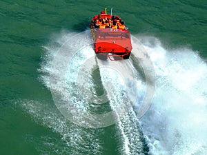 Red speed boat in closeup view. green color water. white wake