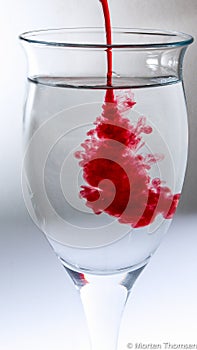 Red splash in glass of water.