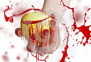 Red splashes on yellow apple in a female hand with long red nails isolated on white background