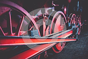 Red spoke wheels with rods and pistons of old train locomotive a