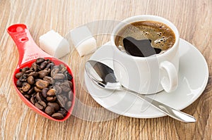 Red spoon with coffee beans, sugar, hot coffee in cup