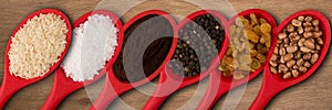 Red spoons with grains and spices, on a wooden background.top wiew.