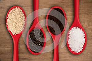 Red spoons with grains and spices, on a wooden background. Top wiew.