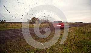 Red sport car driving on the mud