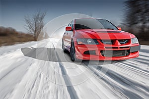 Red sport car driving speed on road at winter daytime