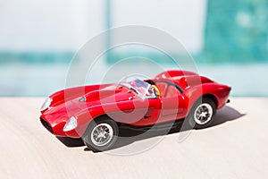 Red sport model car on swimming pool edge with space on blurred background