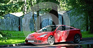Red sports car is parked in the courtyard by the garages