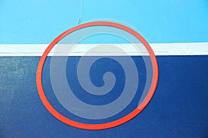 red sports ring on the blue-bluish marking of the badminton court
