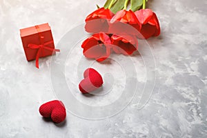 Red spring tulips and gift box on gray background. Happy Valentine`s day. Spring holiday background. Two red hearts. Happy mother