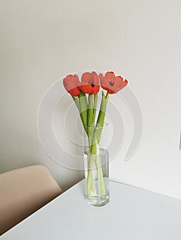 Red spring tulips on a white table on a wicker placemat. Minimalist composition with flowers.