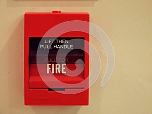 Red square fire alarm box switch on cream wall