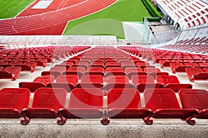 Red stadium seats with red running track and green grass.