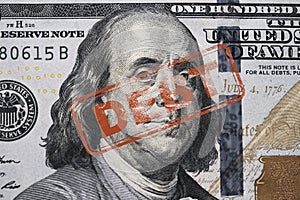 Red stamp debt wording on Benjamin Franklin of one hundred American USD banknote for United States of America government debt