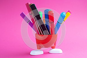 Red stand with white legs and colored markers isolated on a pink background