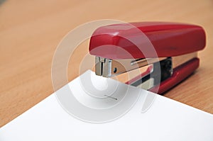 Red stapler fastens white paper