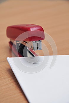 red stapler fastens white paper