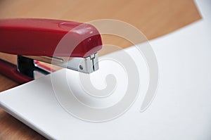 Red stapler fastens white paper