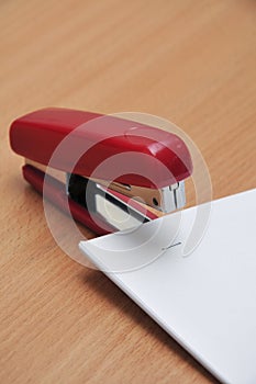 Red stapler fastens white paper