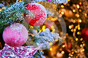 Red star and balls hanging as decorations on a snow-covered Christmas tree, close-up